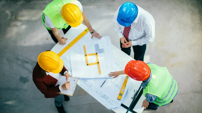 Osoby w kaskach patrzące na projekt